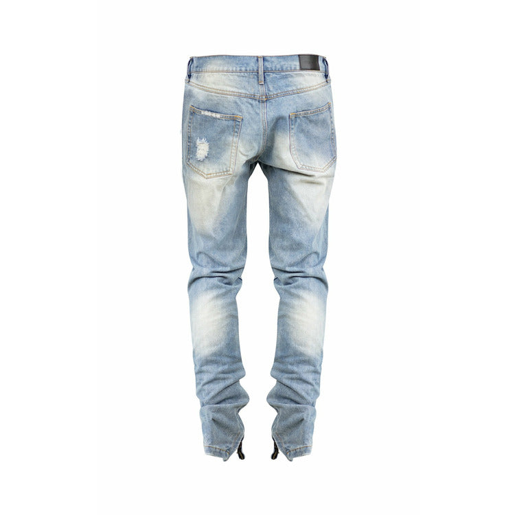 Distressed denim jeans in washed blue with ankle zip